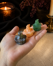 Load image into Gallery viewer, Three assorted 3 cm crystal pumpkins wearing witch hats shown in a hand for scale with warm Halloween candlelight