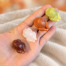 Load image into Gallery viewer, Four approximately 3 cm roast turkey carvings resting in a hand for scale, with cream cloth and a blurred orange background