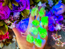 Load image into Gallery viewer, A person's hand holding pieces of Hyalite Opal, also known as Kryptonite, glowing with a green fluorescent light.