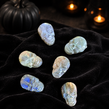Load image into Gallery viewer, Six labradorite skull carvings arranged on black velvet with an elegant Halloween background