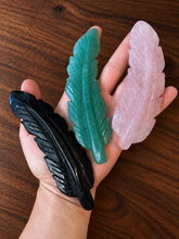 Load image into Gallery viewer, Three carved gemstone feathers shown in hand for scale
