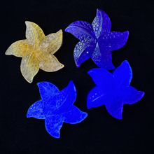 Load image into Gallery viewer, Four Fluorite starfish carvings photographed under ultraviolet light on black velvet
