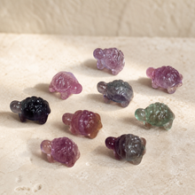 Load image into Gallery viewer, Nine mini fluorite turtle carvings showing purple, green, clear, pink, and smoky natural color variation on pale stone

