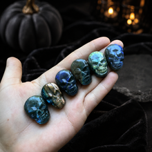Load image into Gallery viewer, Six labradorite skull carvings held in a hand with an elegant dark Halloween background
