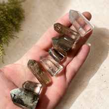 Load image into Gallery viewer, Assorted mini garden quartz towers resting in Eva's hand to show their small scale and varied natural inclusions

