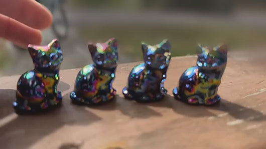 Four rainbow aura cat carvings displayed with a softly blurred warm background