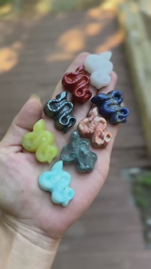 Assorted miniature mixed crystal snake carvings shown in hand