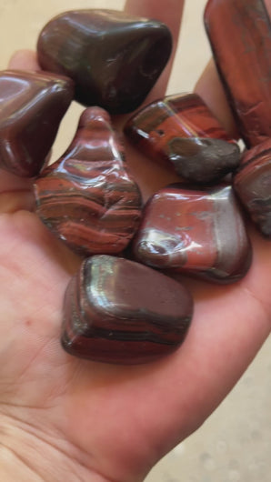 Red Tiger's Eye tumbled stones rotating in natural light