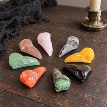 Load image into Gallery viewer, Assorted crystal raven skull carvings on dark wood beside a candle and black gauze.
