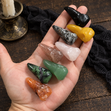 Load image into Gallery viewer, In-hand view showing the shapes and colors of assorted crystal raven skull carvings.

